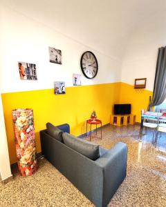 ein Wohnzimmer mit einem Sofa und einer Uhr an der Wand in der Unterkunft Appartamento Al Novecento Novi in Novi Ligure