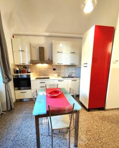 cocina con mesa, sillas y nevera roja en Appartamento Al Novecento Novi, en Novi Ligure