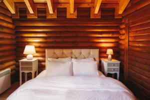 Schlafzimmer mit Holzwänden und einem Bett mit weißer Bettwäsche in der Unterkunft Paradise Chalet in Ano Trikala