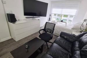 a living room with a couch and a tv and a bed at Stylish room kingsize bed 1 stop from Wembley stadium in Wealdstone