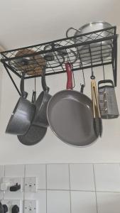 a rack with cooking utensils hanging on a wall at Stylish room kingsize bed 1 stop from Wembley stadium in Wealdstone