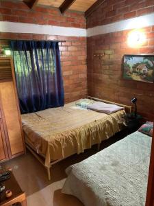1 dormitorio con 2 camas y pared de ladrillo en Cabaña de descanso cerca a Cali, en El Chocho