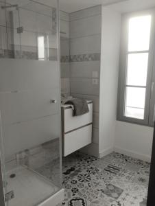 La salle de bains blanche est pourvue d'une douche et d'un lavabo. dans l'établissement Petite maison de ville ernée centre, à Ernée