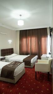 Habitación de hotel con 2 camas y sofá en Gürsoy Kampüs Otel en Beysehir