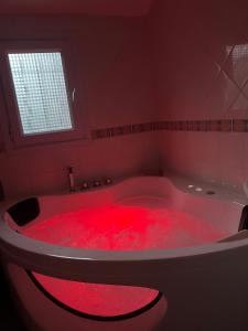una vasca da bagno rossa piena di coloranti rossi di Suite Jacuzzi-Cinéma a Les Clayes-sous-Bois