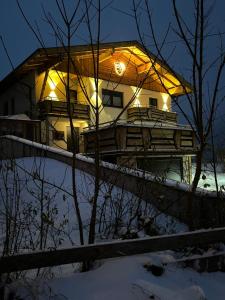 a house with lights on it in the snow at Ferienwohnungen LODGE-B in Weissenbach am Lech