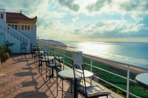 - une rangée de tables et de chaises sur un balcon donnant sur l'océan dans l'établissement Chez Reda, à Assilah