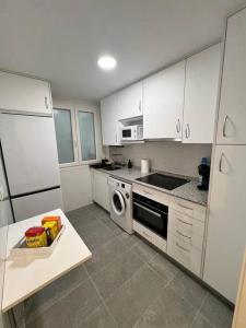een keuken met witte kasten en een fornuis met oven bij Apartamento acogedor in Santander