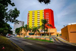 Hotel Santa Irene Guadalajara في غواذالاخارا: مبنى اصفر واحمر على شارع فيه نخيل