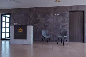 2 sillas en una habitación con una pared de piedra en Hotel y Villas Costa del Sol en Mérida