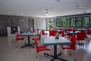 un restaurant avec des chaises rouges, des tables et des fenêtres dans l'établissement Hotel y Villas Costa del Sol, à Mérida