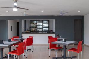 a dining room with tables and red chairs at Hotel y Villas Costa del Sol in Mérida