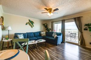 a living room with a blue couch and a table at Bayfront Texas Escape with Balcony and Pool Access! in Rockport