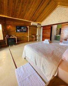 a bedroom with a large bed and a television at Collina Beach in Amontada