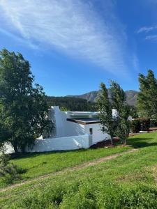 a white house with trees and a grass field at Watsonia Cottage at Waboom Family Farm in Stanford +27 photos