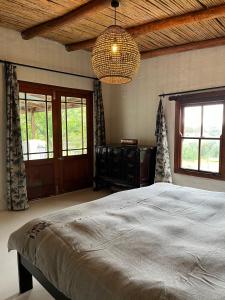 a bedroom with a large bed and a chandelier at Watsonia Cottage at Waboom Family Farm in Stanford