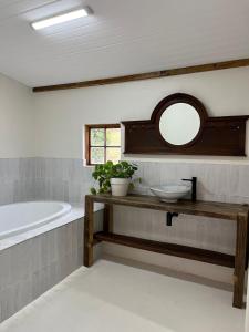 a bathroom with a tub and a sink and a mirror at Watsonia Cottage at Waboom Family Farm in Stanford