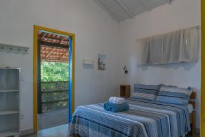 a bedroom with a bed with a blue and white striped blanket at Vila Coco Dendê - Algodões in Marau