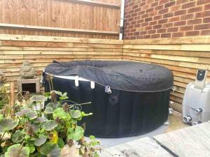 a black tub with a cover on it next to a fence at Pretty fancy staycation - South East London / Kent in Bromley