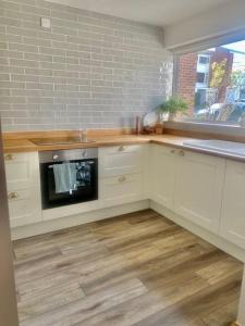 a kitchen with white cabinets and a sink and an oven at Pretty fancy staycation - South East London / Kent in Bromley
