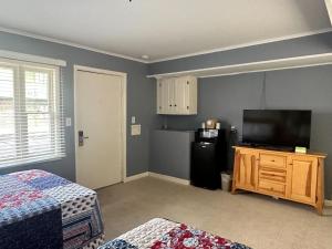 een kamer met een televisie en een kleine koelkast bij Community Court Motel in Saratoga Springs