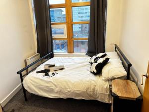 a bed in a room with a large window at Luxury Two Bedroom En-Suité Apartment in Manchester