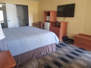 a hotel room with a bed and a flat screen tv at Oakridge Inn & Suites in Oakridge
