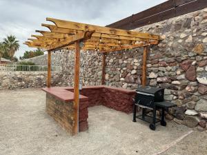 a wooden pergola with a grill next to a stone wall at Peaceful West: 4BR Dusk Haven in El Paso
