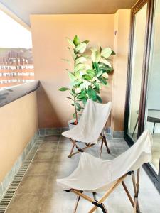 uma varanda com duas cadeiras e um vaso de plantas em El Pisín de Avilés. Parking / WIFI em Avilés