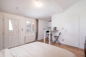 a white bedroom with a bed and a desk at Lumignons Lyonnais - Doua in Villeurbanne