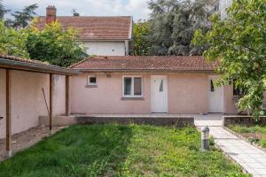 a brick house with a white door and a yard at Lumignons Lyonnais - Doua in Villeurbanne +3 photos