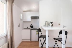 a white kitchen with a table and two chairs at Lumignons Lyonnais - Doua in Villeurbanne