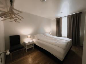 una camera da letto con un letto, una sedia e una finestra di Gamli Skólinn Húsavík a Húsavík
