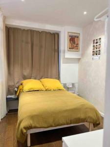 ein Schlafzimmer mit einem Bett mit gelber Bettwäsche und einem Fenster in der Unterkunft La Galerie Dinard in Dinard