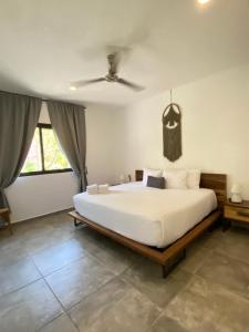 a bedroom with a large white bed and a ceiling at Panacea Condo Tulum in Tulum