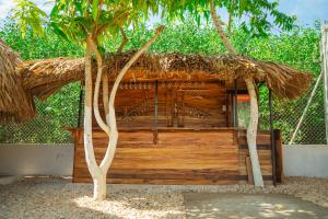 een houten hut met een rieten dak en twee bomen bij Hotel Punta Piedra in Coveñas