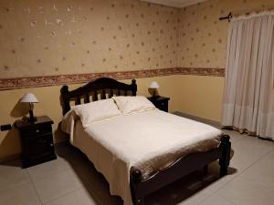 a bedroom with a bed and two night stands with lamps at Marcos Paz temporario in San Miguel de Tucumán