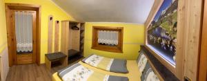 a small room with two beds and a yellow wall at Baita La Fonte in Livigno