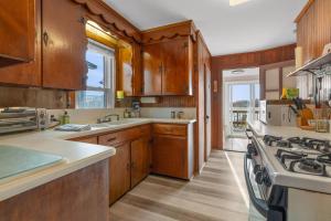 a kitchen with wooden cabinets and a stove top oven at Pinehurst Sunset Beach Cottage in Wareham