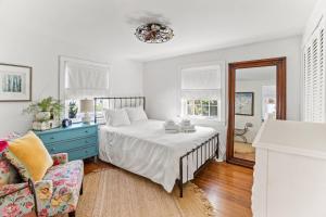 1 dormitorio blanco con 1 cama y 1 silla en Cottage Serenity Haven, en Barnstable