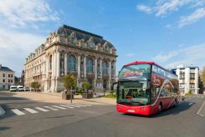 a red double decker bus driving past a building at Appart proche plage Calais in Calais