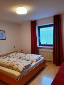ヴァルダーオラにあるApp. Brunnerのベッドルーム1室(ベッド1台付)、赤いカーテン付きの窓が備わります。