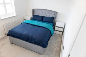 a bedroom with a bed with a blue comforter at Private room in a new build in Heanor