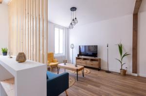 ein Wohnzimmer mit einem blauen Sofa und einem TV in der Unterkunft La Saint-Quentinoise chambre privée amande in Saint-Quentin