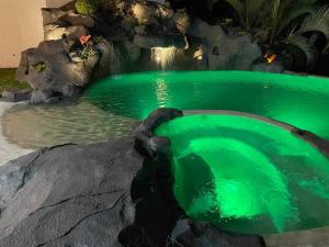einem Pool mit grünem Wasser und einem Wasserfall im Hintergrund in der Unterkunft Casa Vista al Lago de Golf in Texcalpan