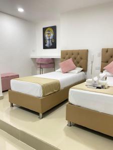 a bedroom with two beds and a table and chairs at Hotel Hernández CTG in Cartagena de Indias
