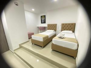 1 dormitorio con 2 camas y mesa en Hotel Hernández CTG, en Cartagena de Indias