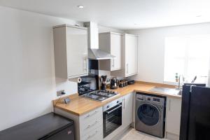 a kitchen with white cabinets and a washer and dryer at Private room in a new build in Heanor