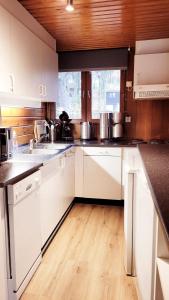 a kitchen with white cabinets and a wooden floor at Chalet La Boverie 195 in Rendeux