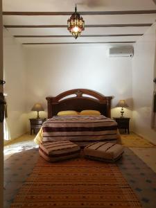 1 dormitorio con 1 cama con 2 mesas y una lámpara de araña en Chez Kossai Atlas Farm, en Chtawna